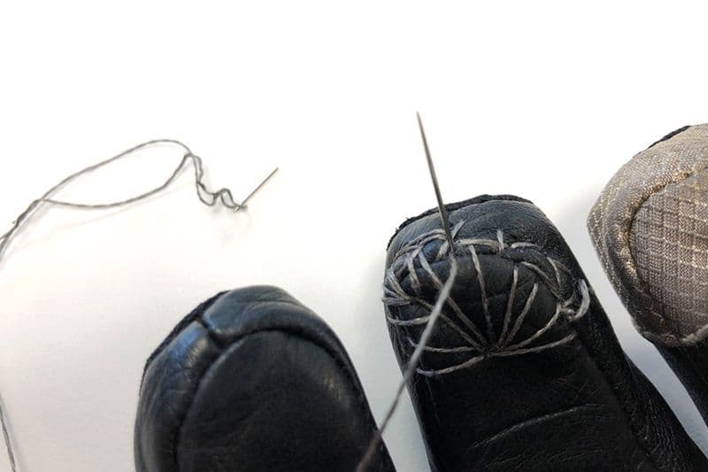 Detailansicht vom Motorradhandschuh mit Nadel und Silberfaden